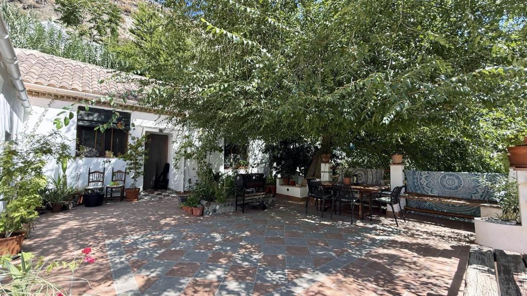 Un patio con un árbol y una mesa y sillas. en Mshome La Noble, en Monachil