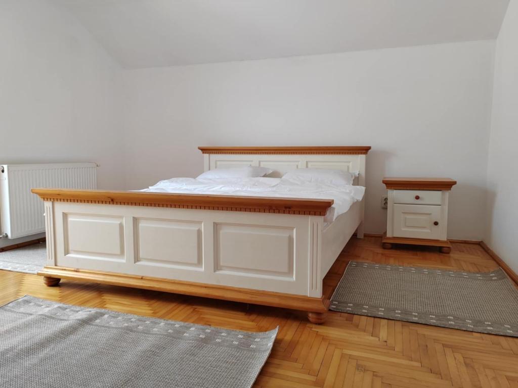 a bedroom with a white bed and a wooden floor at Casa spațioasă in oras in Suceava