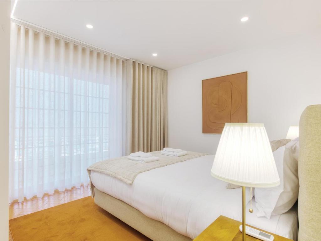 a white bedroom with a bed and a window at Vita Portucale ! Almada Trendy Retreat in Almada