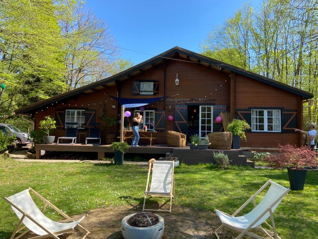 a woman standing in front of a log cabin at Chalet dans les bois -Domaine Privé-5 Etangs in Bazoches-sur-le-Betz