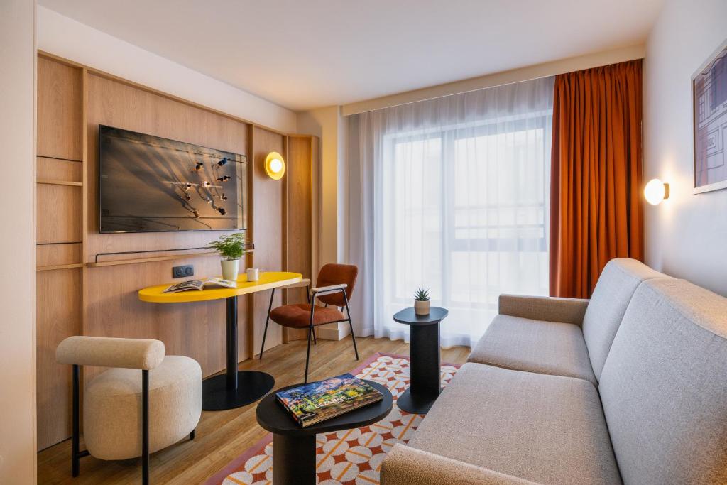 a living room with a couch and a table at Citadines République Paris in Paris