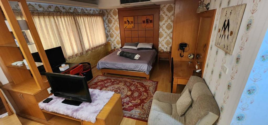 a small room with a bedroom with a bed and a chair at JOLLY GUESTHOUSE & RESTAURANT in Pattaya