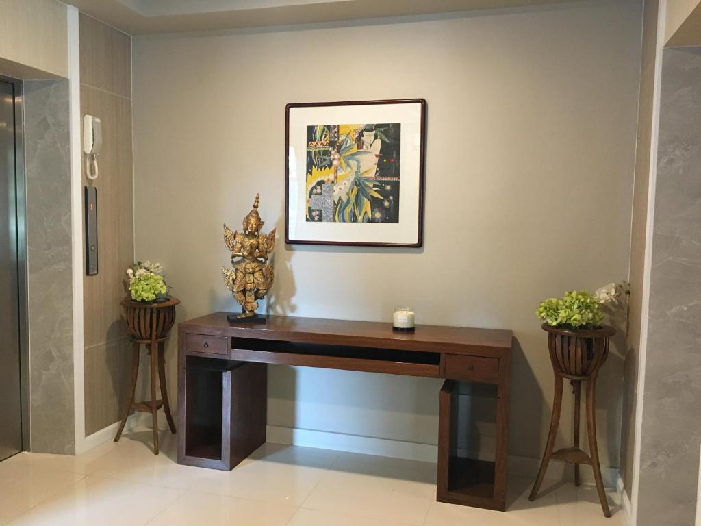 A compact hotel console table in a polished hallway beside an elevator.