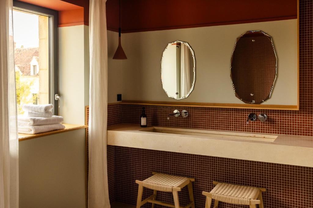 Un baño con dos espejos y un lavabo con dos taburetes. en Le Val Gaudry, en Montgaudry