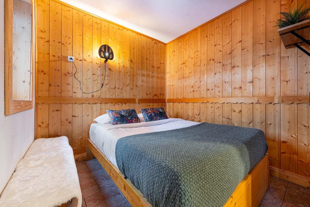 a bedroom with a bed in a wooden wall at Central Apartment In Heart of Val Thorens, Ski In-Out with WiFi in Val Thorens