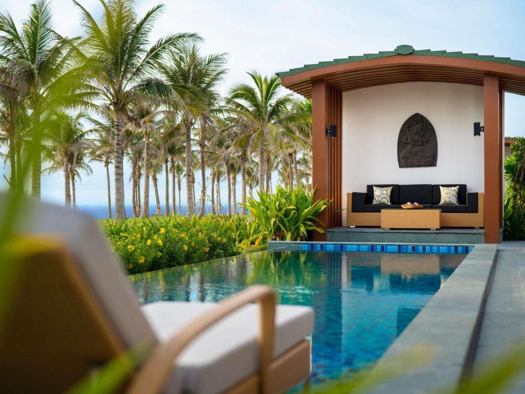 a resort with a swimming pool and palm trees at Mövenpick Resort Cam Ranh in Cam Ranh