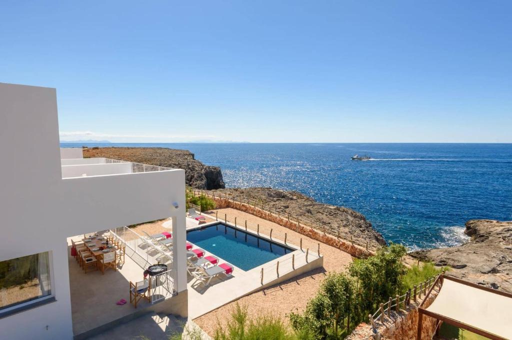 a house with a swimming pool next to the ocean at Villa Aguamarina by Villa Plus in Cala en Forcat