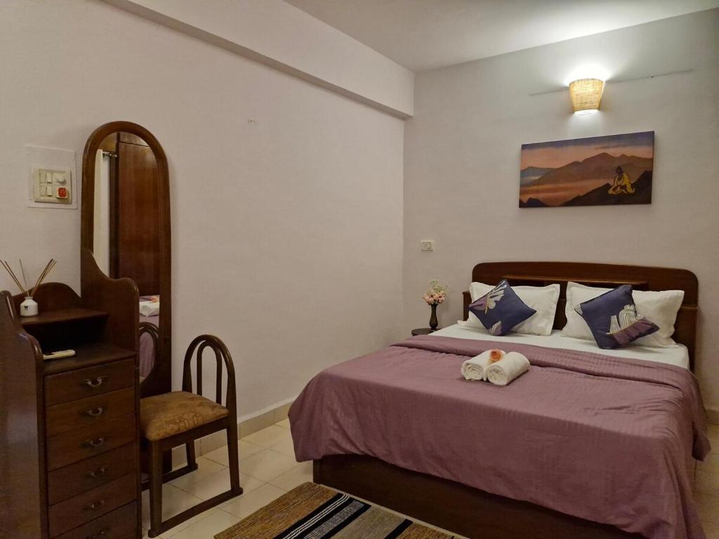 a bedroom with a bed and a chair and a dresser at Cozy Cabana - Maynard Palace in Benaulim