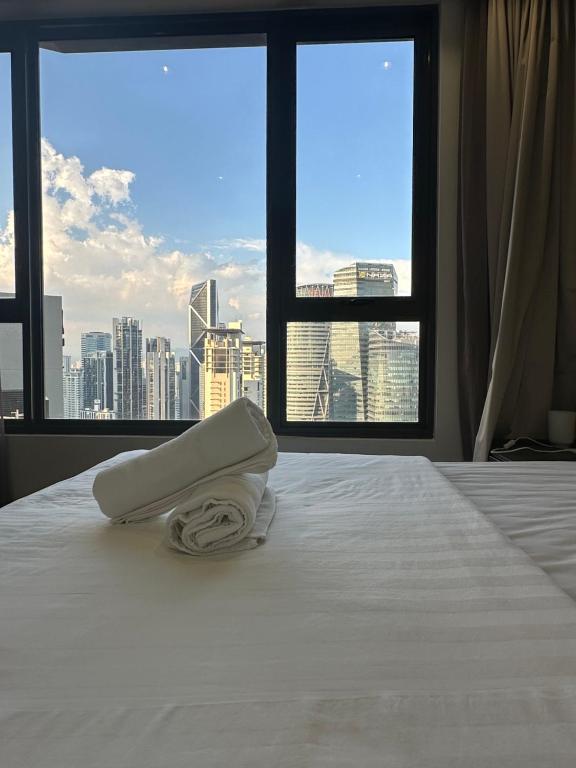 a bedroom with a white bed with a view of a city at 8 Kia Peng by 8 Suites kL in Kuala Lumpur