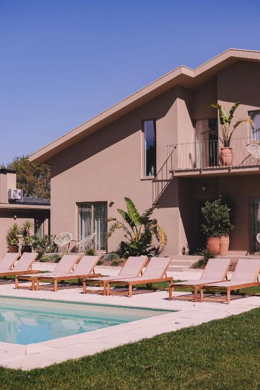 a row of lounge chairs next to a swimming pool at Casa Pacata, Beachside Escape in Labruge
