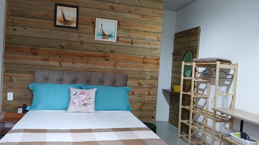 a bedroom with a wooden accent wall and a bed at Suite 66 privativa, 11km da vila Germânica in Blumenau