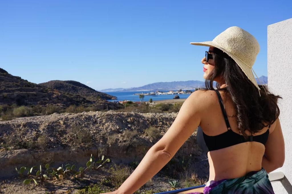 una donna in bikini, cappello e occhiali da sole di Aptos Laguna Premium a Puerto de Mazarrón