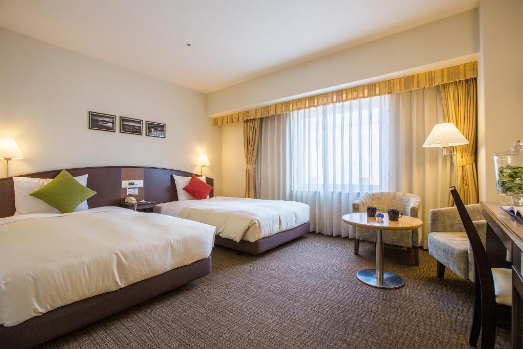 a hotel room with two beds and a table at Hotel Resol Hakodate in Hakodate