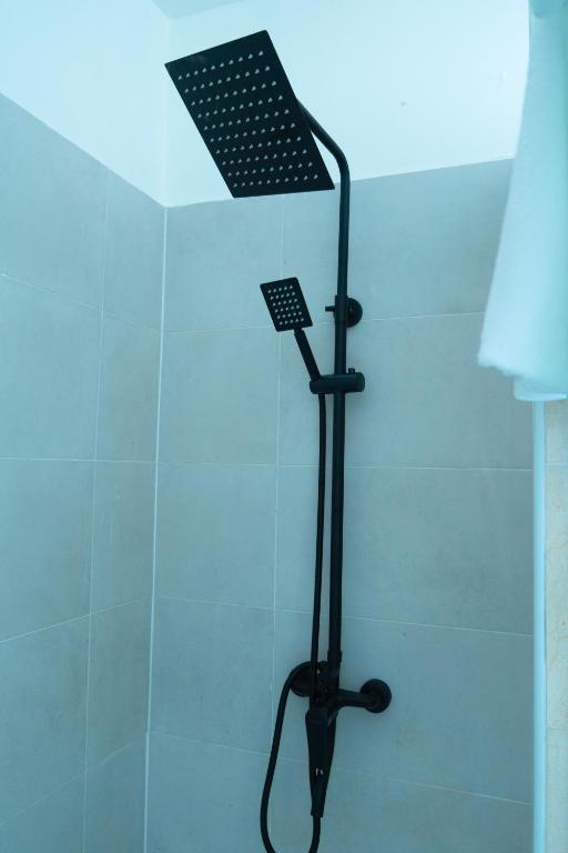 a shower with a black shower head in a bathroom at EMY guest HOUSE in Kofa