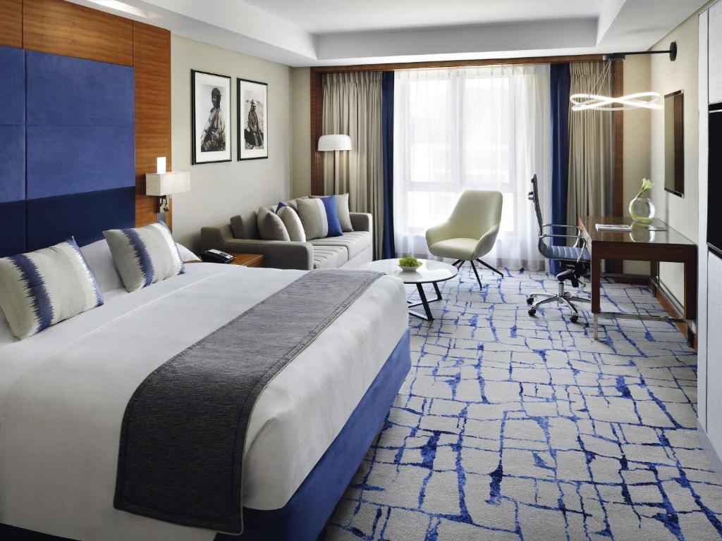 a hotel room with a large bed and a living room at Mövenpick Hotel & Apartments Bur Dubai in Dubai