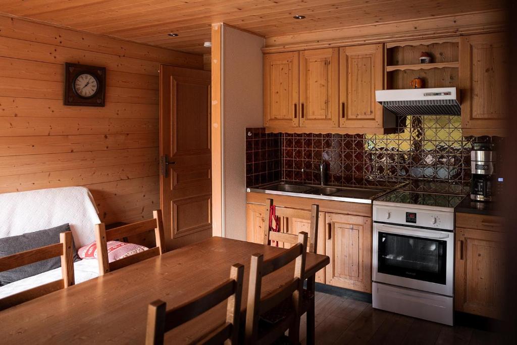 a kitchen with wooden cabinets and a table with chairs at Chardonneret 3 in La Clusaz