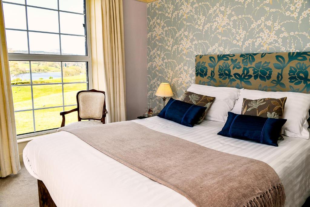a bedroom with a large bed with blue pillows and a window at Ees Wyke Country House in Near Sawrey