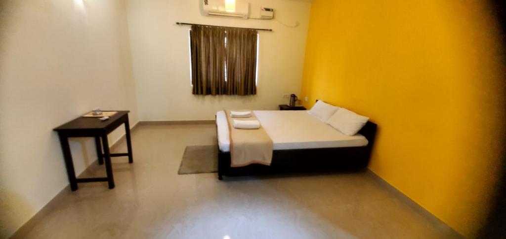 a small bedroom with a bed and a table at Maggie's Guest House By NNR in Goa