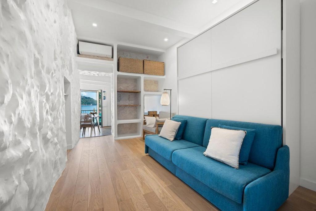 a blue couch in a living room with a stone wall at LE SANTORIN - Vue Exceptionnelle - au coeur de la Vieille Ville in Menton