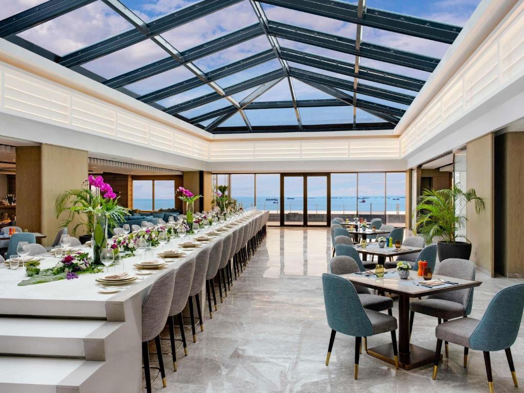 a dining room with tables and chairs and a glass ceiling at Admiral Hotel Manila - MGallery Collection in Manila