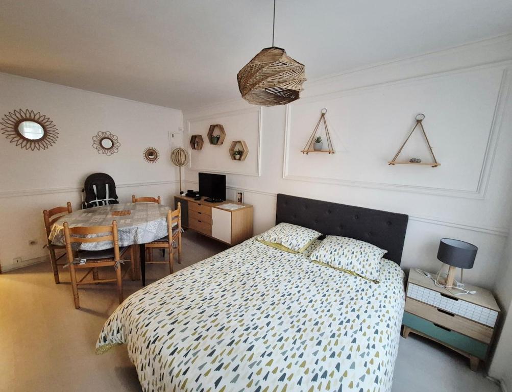 Un dormitorio con una cama y una mesa con sillas. en Studio cocooning proche plage & centre, en Trouville-sur-Mer