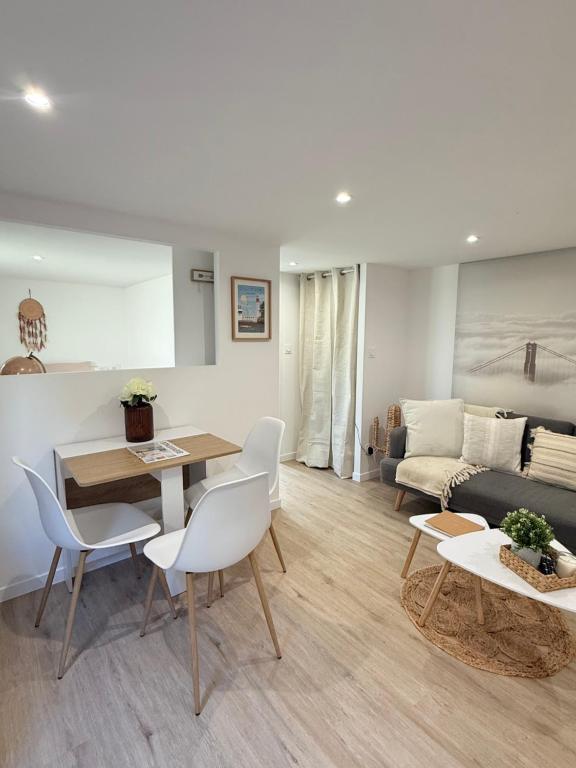 uma sala de estar com uma mesa, cadeiras e um sofá em Les Secrets d Ouistreham em Ouistreham