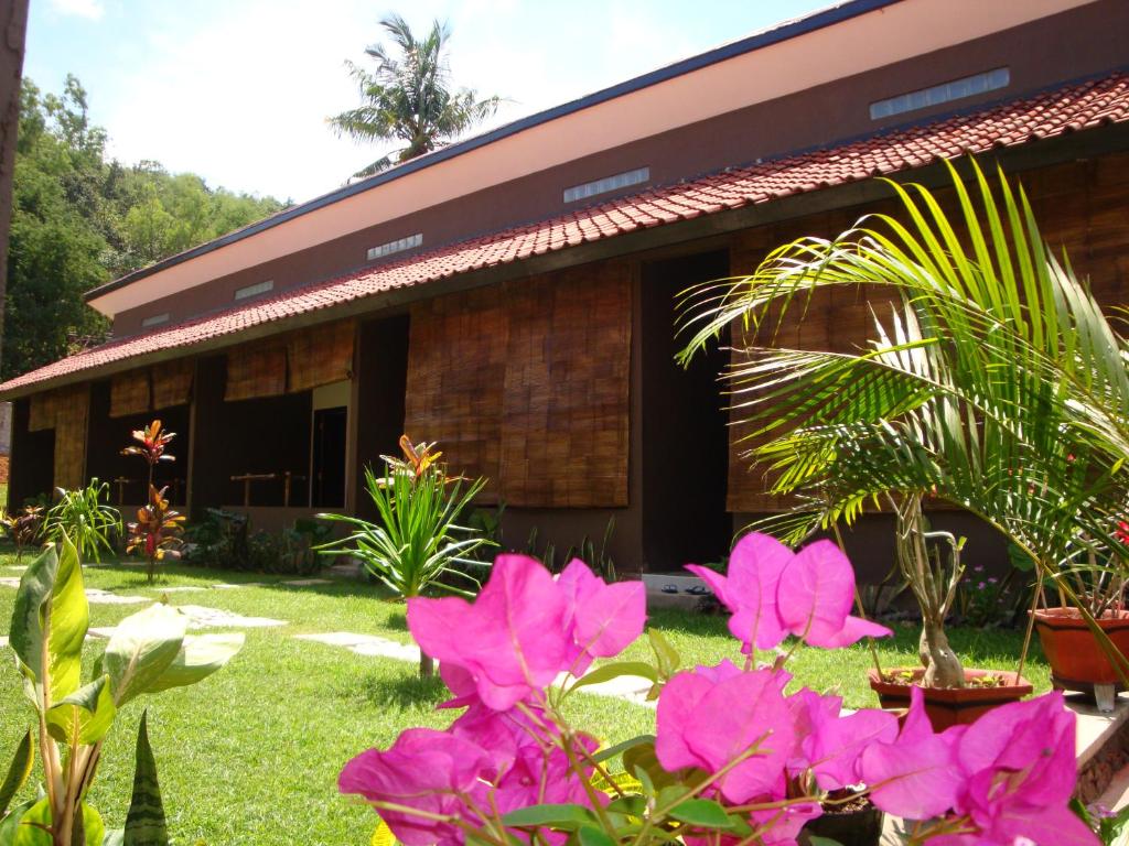 a house with pink flowers in front of it at Relaxing Homestay in Kuta Lombok
