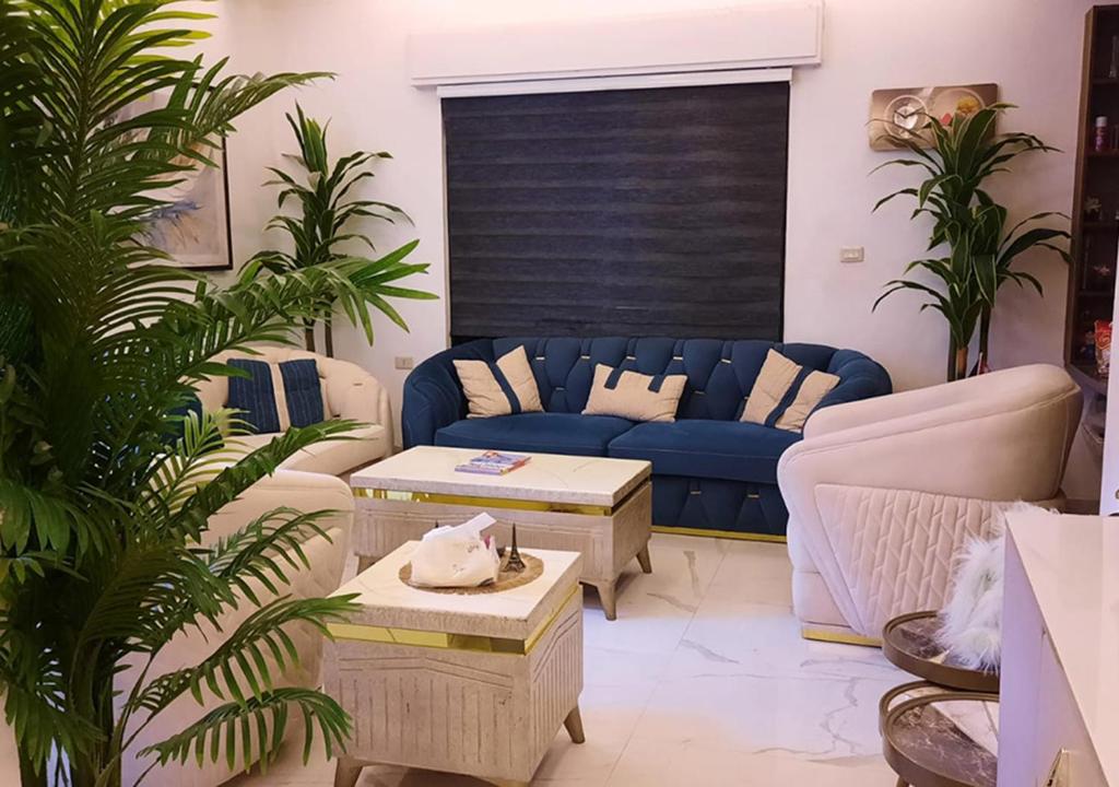 a living room with a blue couch and some plants at Modern Apartment in Amman in Amman
