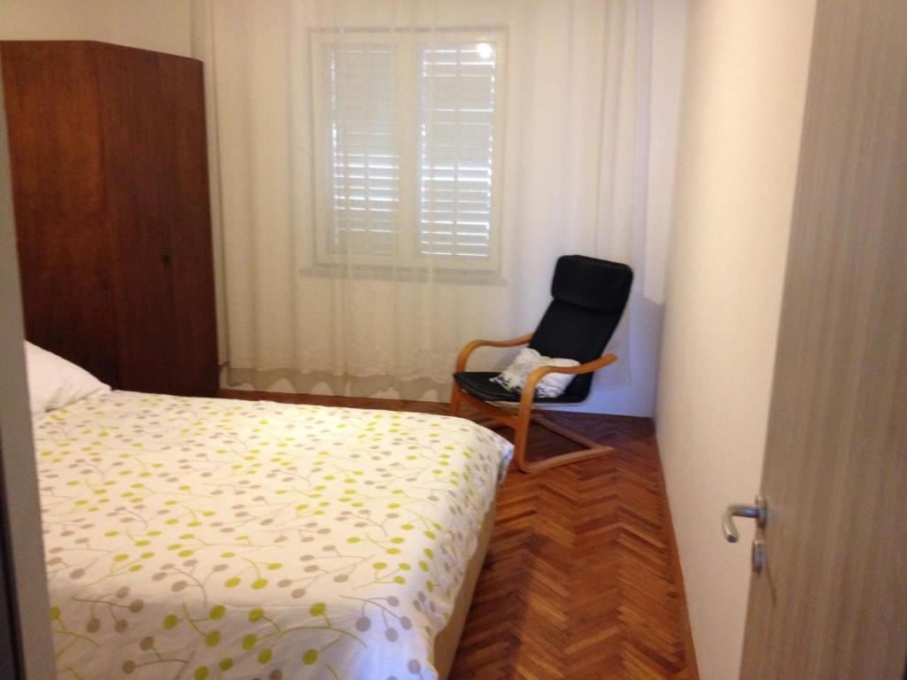 ein Schlafzimmer mit einem Bett und einem Stuhl neben einem Fenster in der Unterkunft Apartment Goreta in Trogir