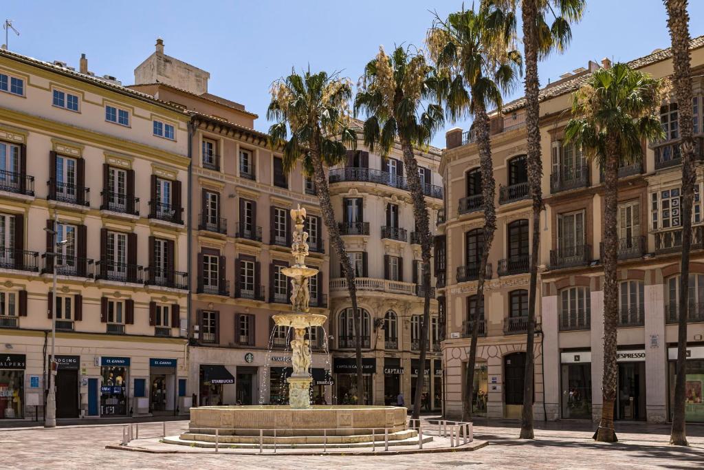 a fountain in front of a building with palm trees at NOMADIA en LARIOS STREET in Málaga