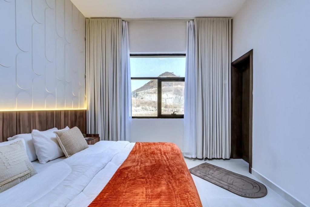 a bedroom with a large bed with a large window at The Living khorfakan Cornish 2 in Khor Fakkan