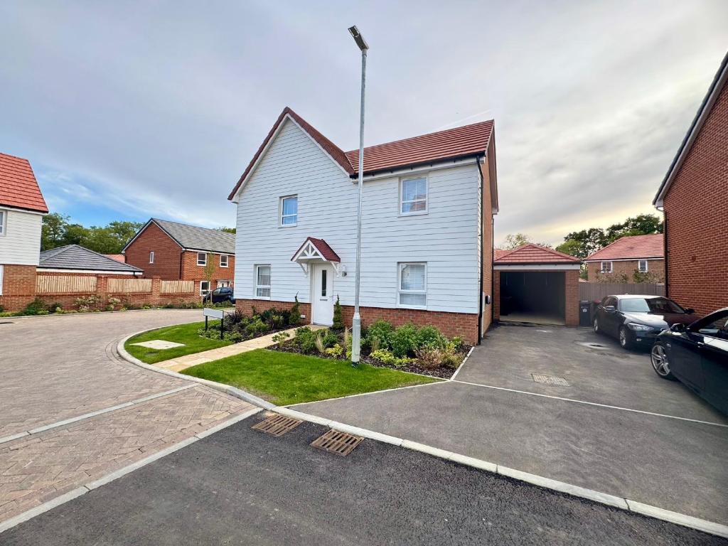 a white house with a car parked in a driveway at Detached 4BR House - Private Garden, Garage & Parking - Perfect for Long Stays, Families, Contractors in Canterbury