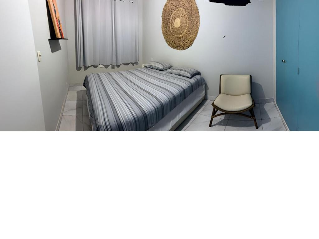 a small bedroom with a bed and a chair at Praia do Tombo - Aconchego no Guarujá in Guarujá