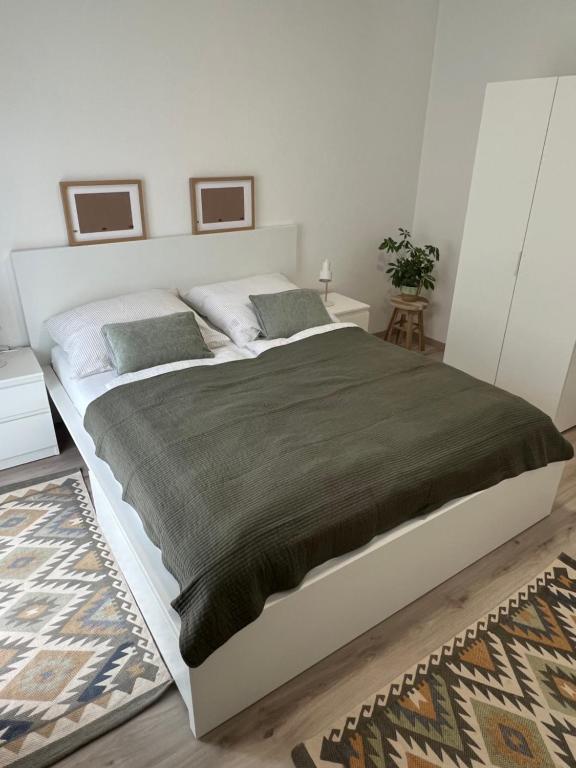 a white bedroom with a large bed with two pillows at Prague Airport Apartment in Tuchoměřice