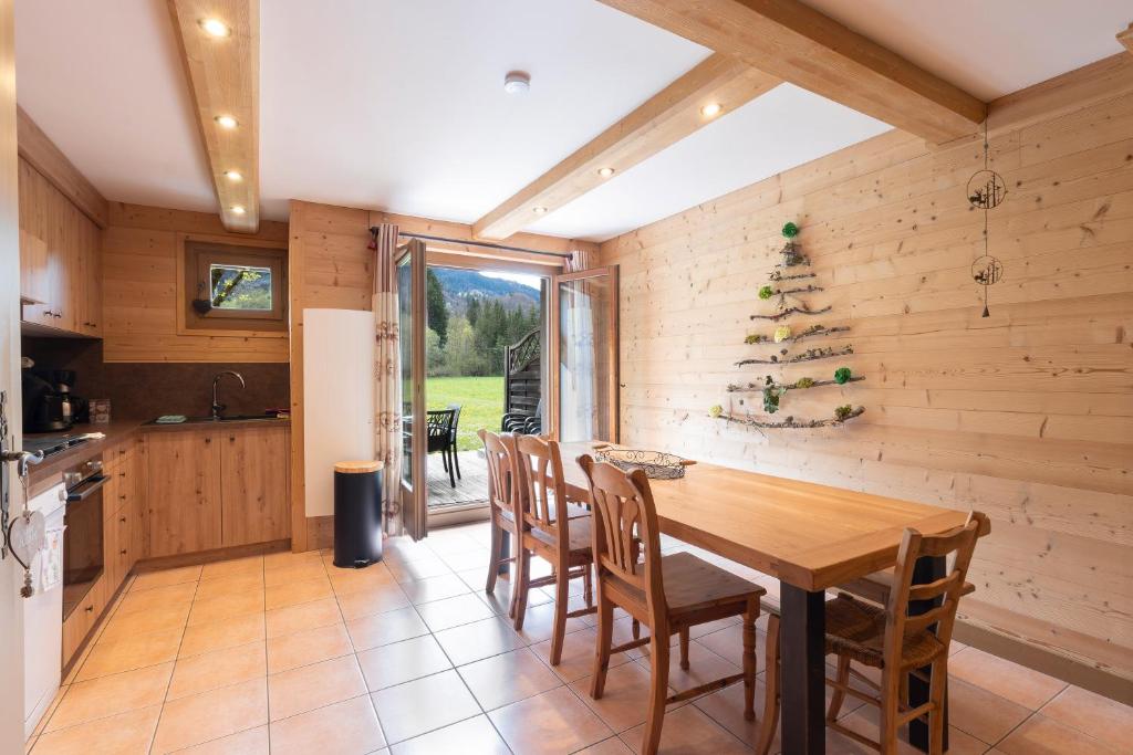 a kitchen and dining room with a wooden table and chairs at Chalet Triplex avec Piscine - Sauna in Samoëns