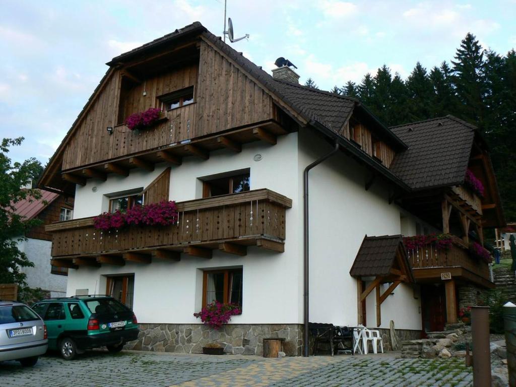 a house with a wooden roof and a balcony at Apartmány U Vaců in Železná Ruda