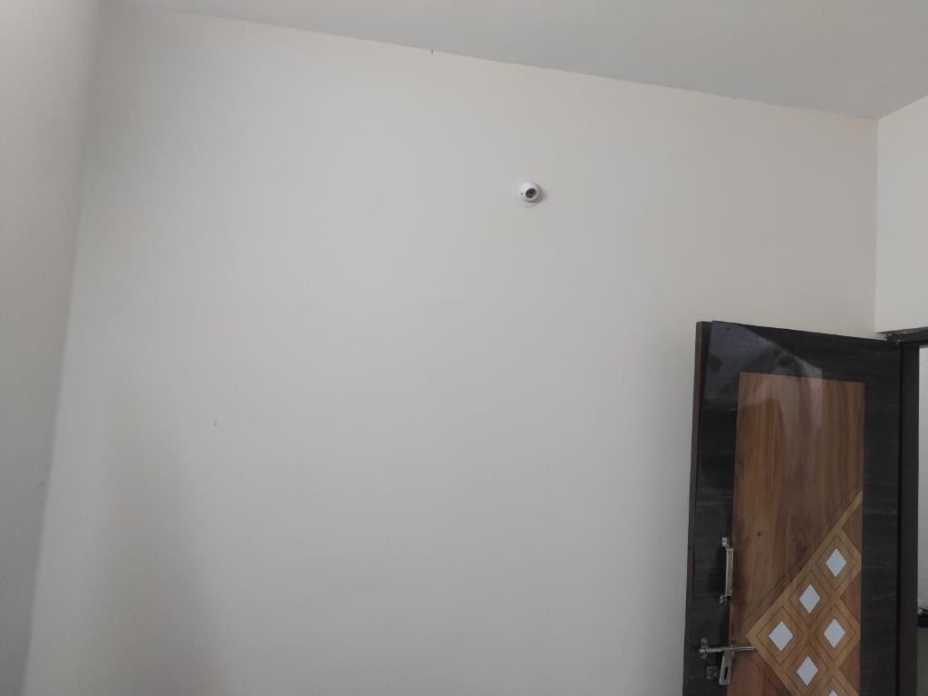 a room with a white wall and a wooden cabinet at Zenobia House in Udupi