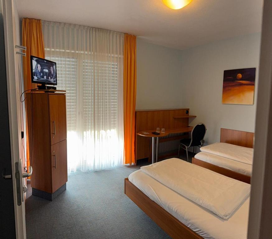 a hotel room with two beds and a television at SVG Hotel Diversi in Ludwigshafen am Rhein