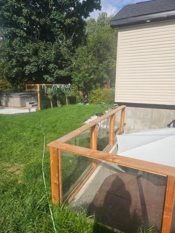 a glass deck next to a house with a yard at Chambre de répit au bord de l'eau in Chambly