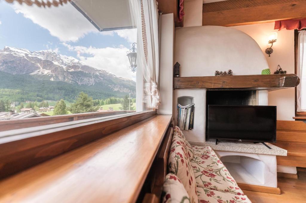 een woonkamer met een groot raam en een televisie bij Casa Verocai - Mountain View Terrace & Parking in Cortina dʼAmpezzo