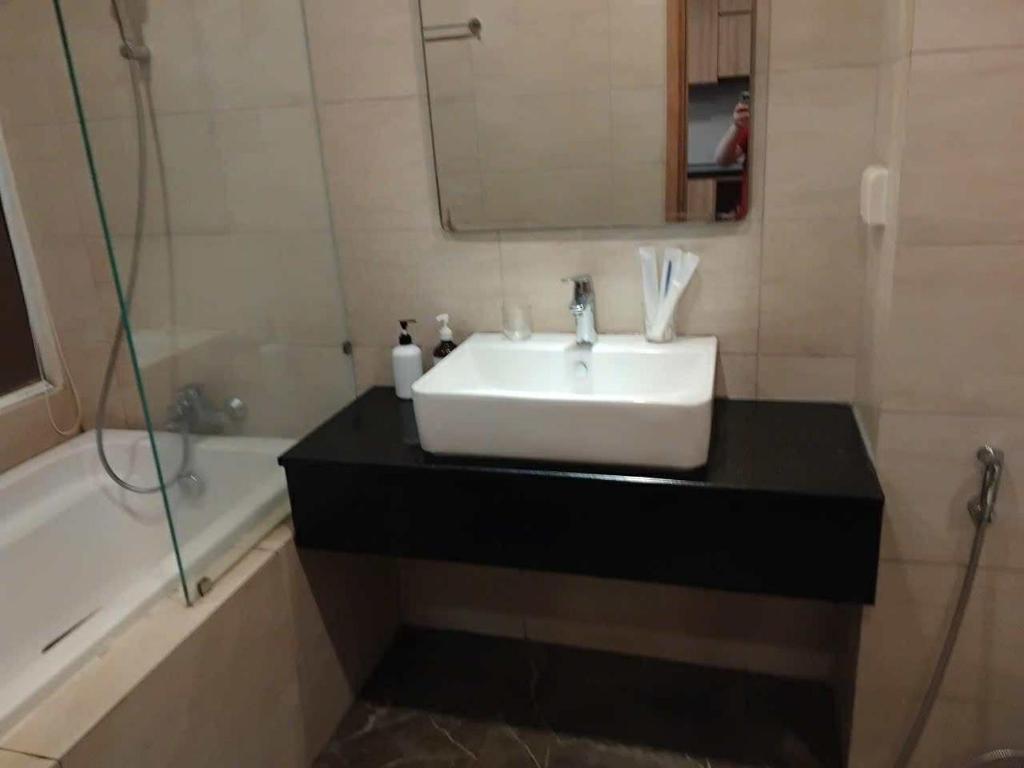 a bathroom with a white sink and a bath tub at Lemon Apartment Quy Nhơn in Quy Nhon