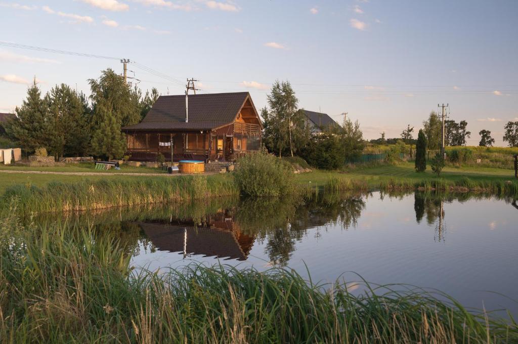 una baita di tronchi accanto a un lago con una casa di Dom Nad Stawem z Balią a Jaromierz