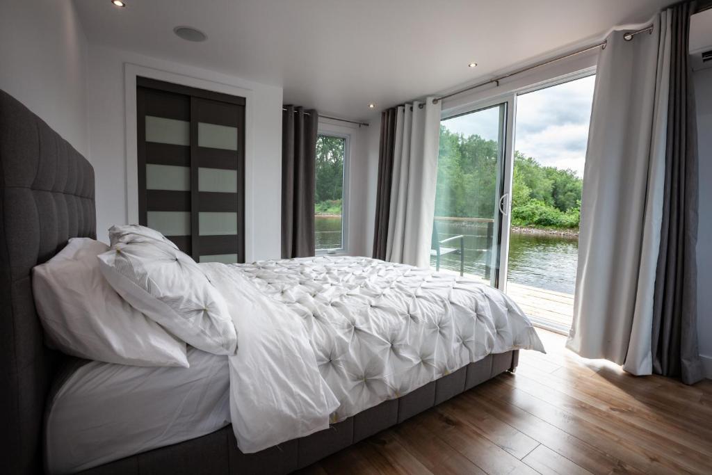 a bedroom with a large bed and a large window at Yacht Club de Trois-Rivières 2 - Maison flottante in Trois-Rivières