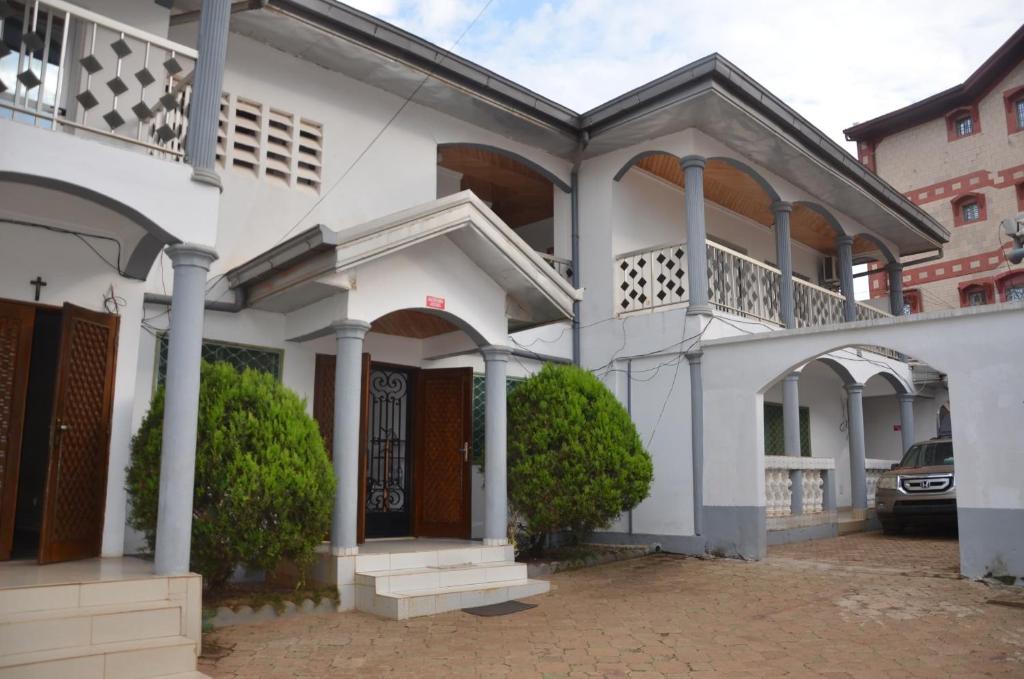 a white house with a balcony and a driveway at VICTOR & VICTORY GUEST HOUSE DAMAS-RAIL OBOBOGO Source in Yaoundé