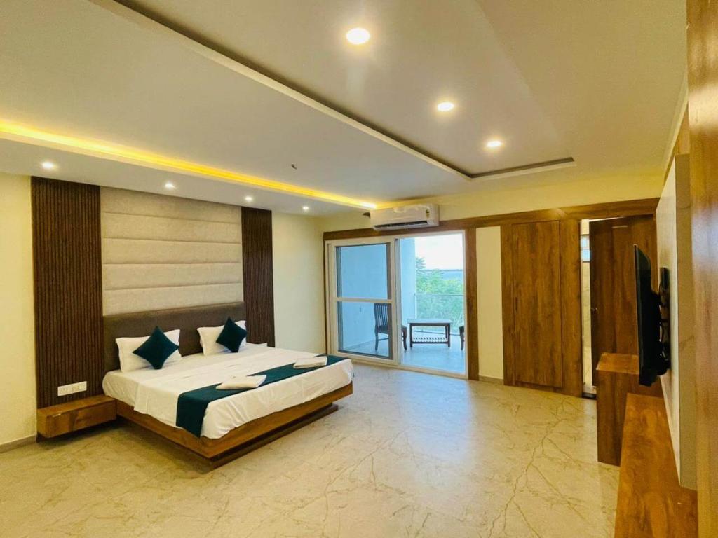 a bedroom with a large bed and a balcony at Blue Lagoon Inn Resort in Hosa Kannambādi