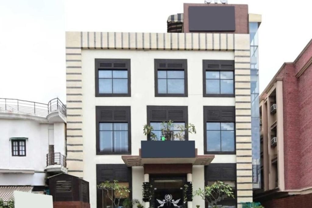 a large white building with black windows at Hotel O Daraganj Ghat Prayagraj Formerly Purohit Inn in Colonelganj