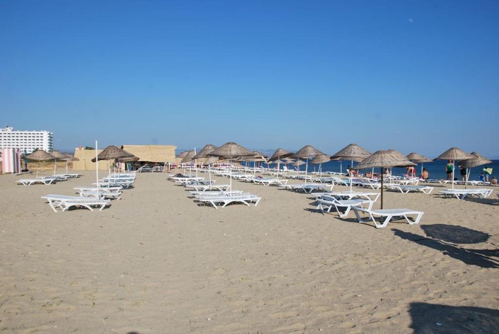 una fila de sillas y sombrillas en una playa en Efsanem Hotel, en Ayvalık