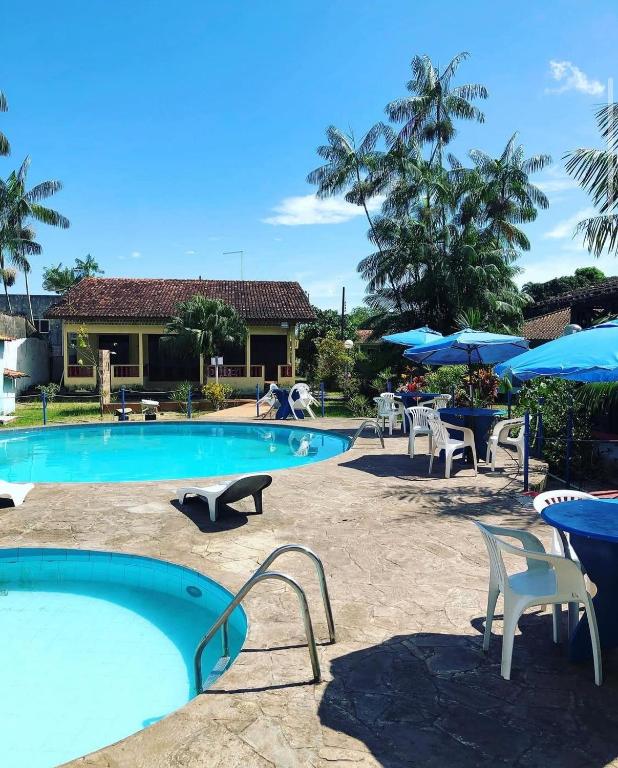 a swimming pool with tables and chairs and umbrellas at Hotel Porto Arthur in Belém