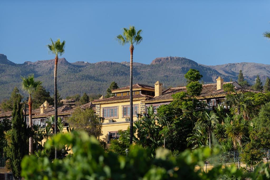a building with palm trees and mountains in the background at KARAT El Nogal Hotel Boutique & Spa in Escalona