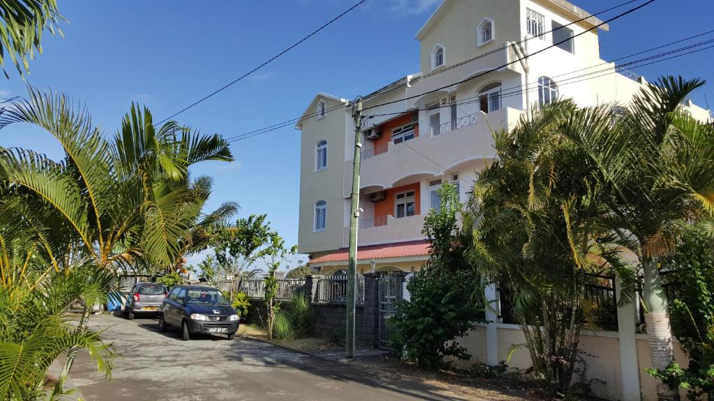 a white building with cars parked in front of it at The Impala Mauritius in Trou aux Biches
